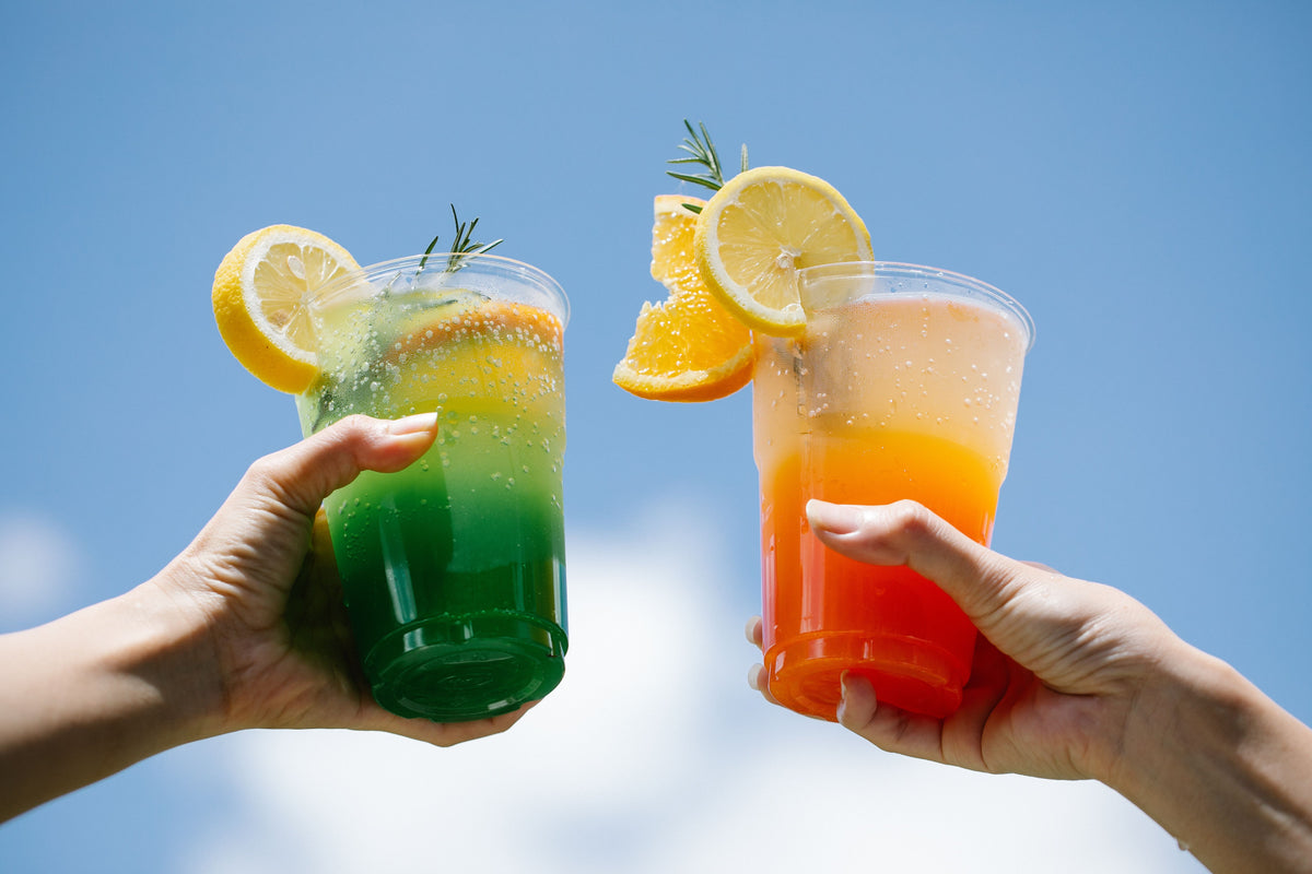 Two colorful sparkling fruit drinks garnished with citrus.